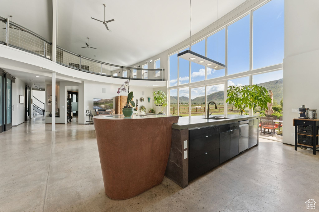 Kitchen featuring a sink, a kitchen island with sink, a towering ceiling, modern cabinets, and stainless steel dishwasher