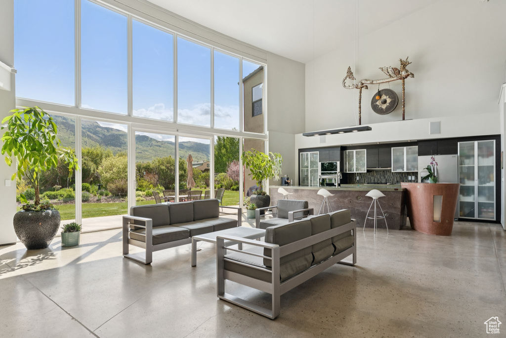 Living area with a towering ceiling, healthy amount of natural light, a mountain view, and floor to ceiling windows