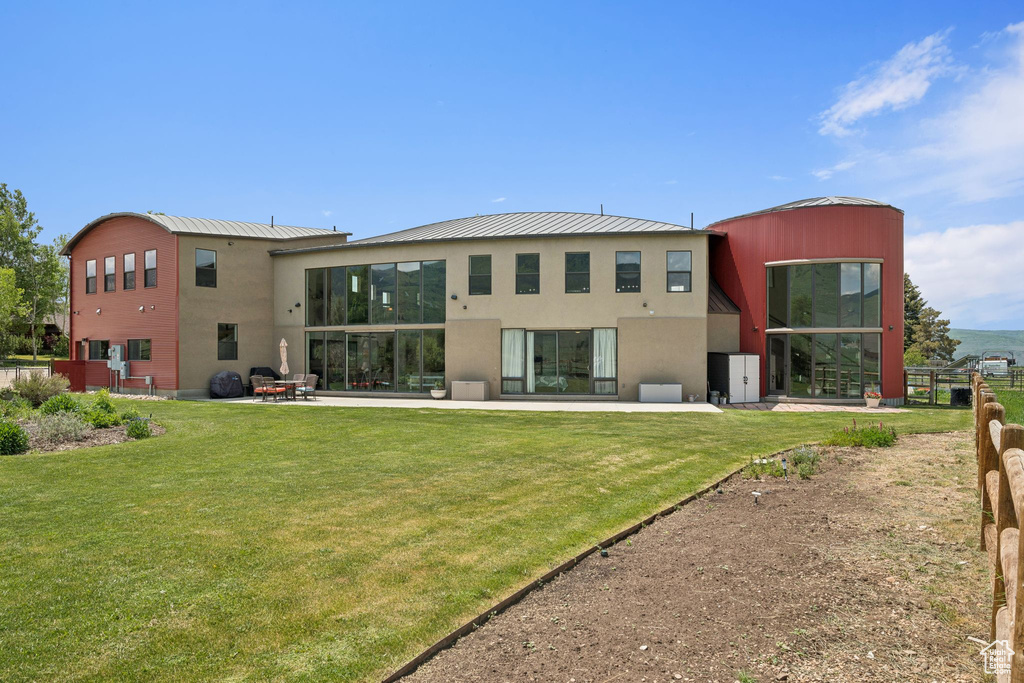 Rear view of property featuring a yard, stucco siding, and a standing seam roof