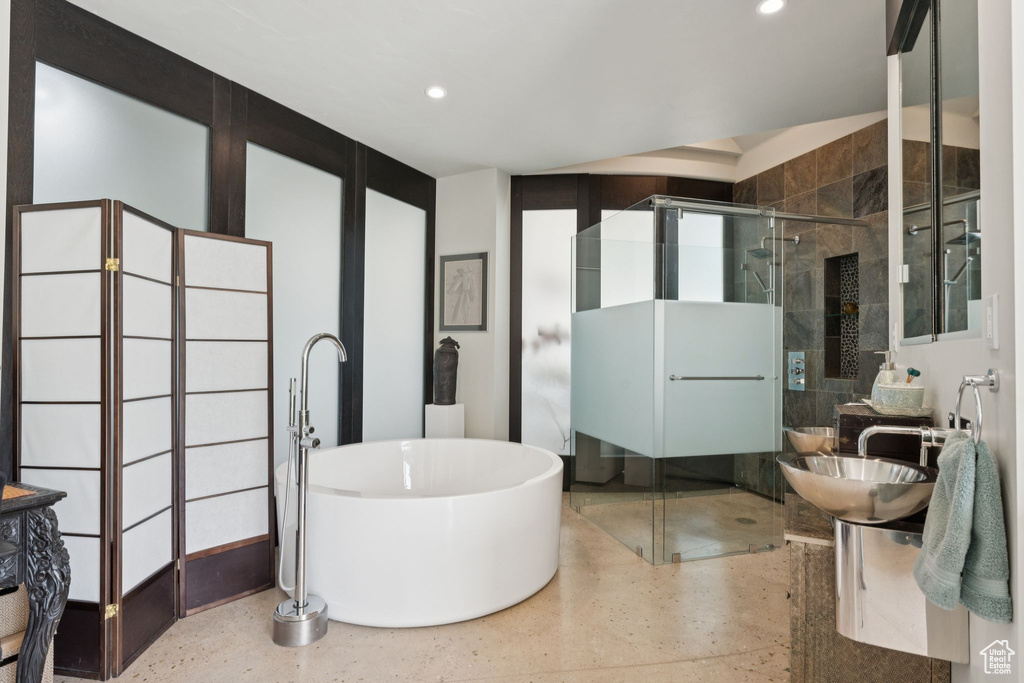 Full bathroom with a shower stall, a freestanding bath, recessed lighting, speckled floor, and a sink