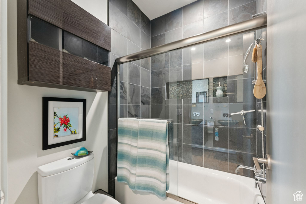 Bathroom with toilet and shower / bath combination with glass door