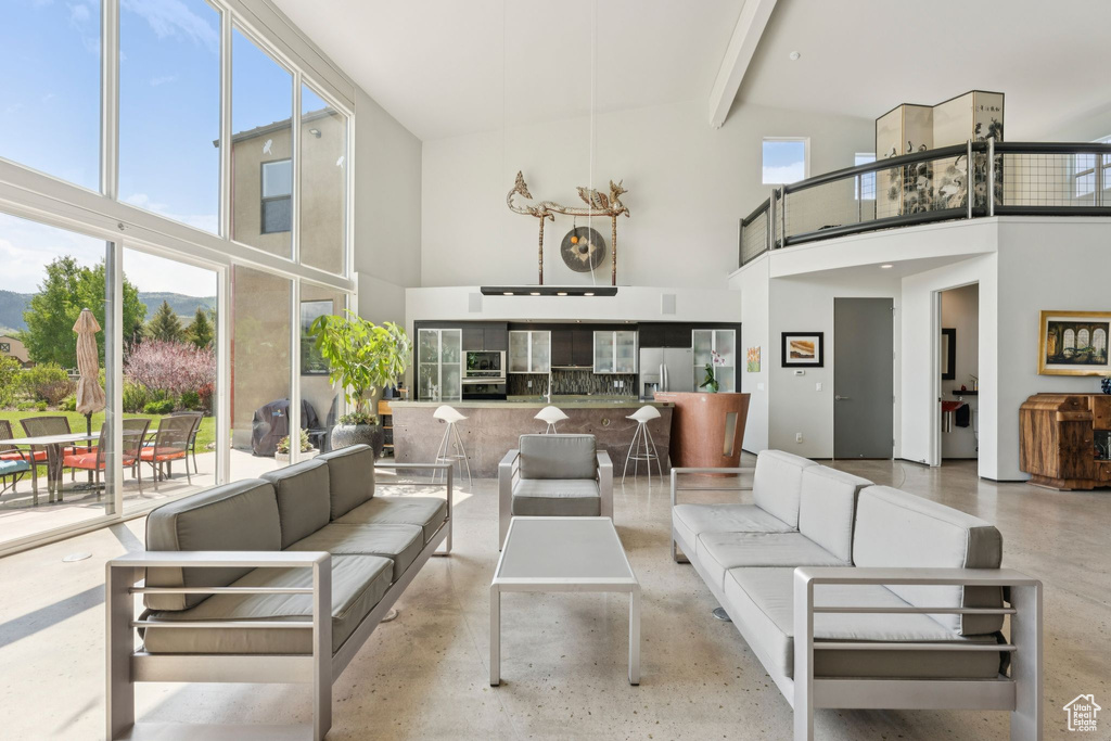 Living room with a towering ceiling, concrete floors, and beamed ceiling