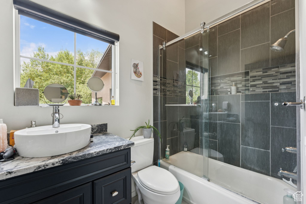 Full bathroom featuring vanity, enclosed tub / shower combo, and toilet
