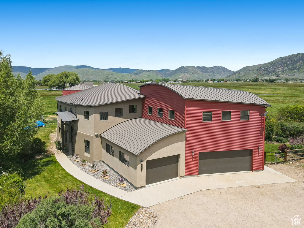 View of front of home featuring a standing seam roof, a mountain view, concrete driveway, metal roof, and an attached garage