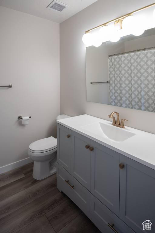 Full bath featuring vanity, toilet, wood finished floors, and baseboards