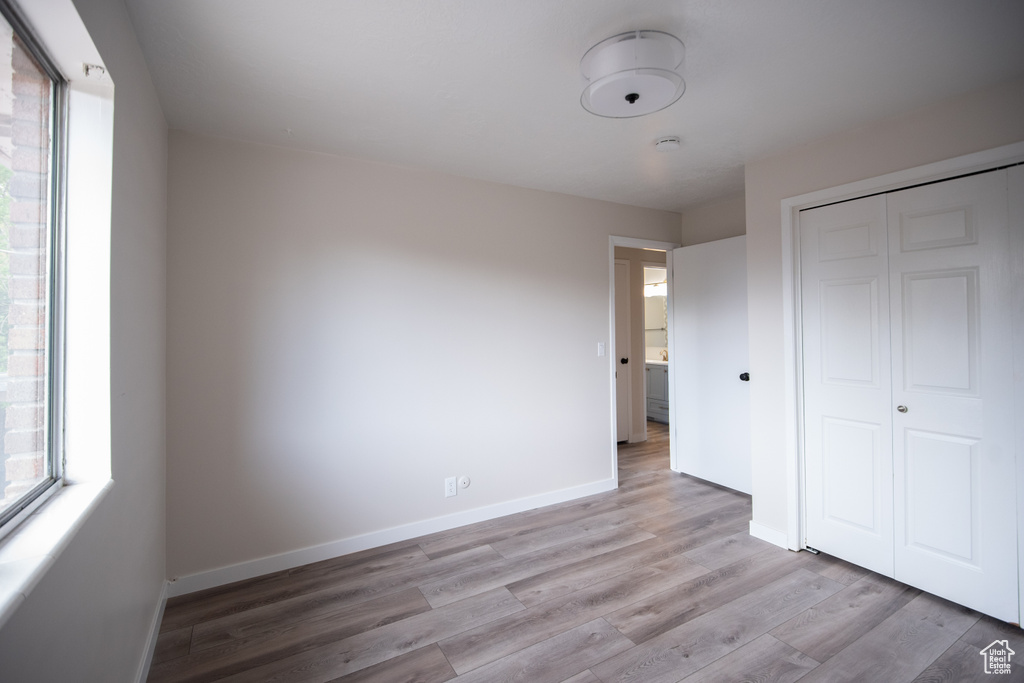 Unfurnished bedroom featuring wood finished floors, baseboards, and a closet