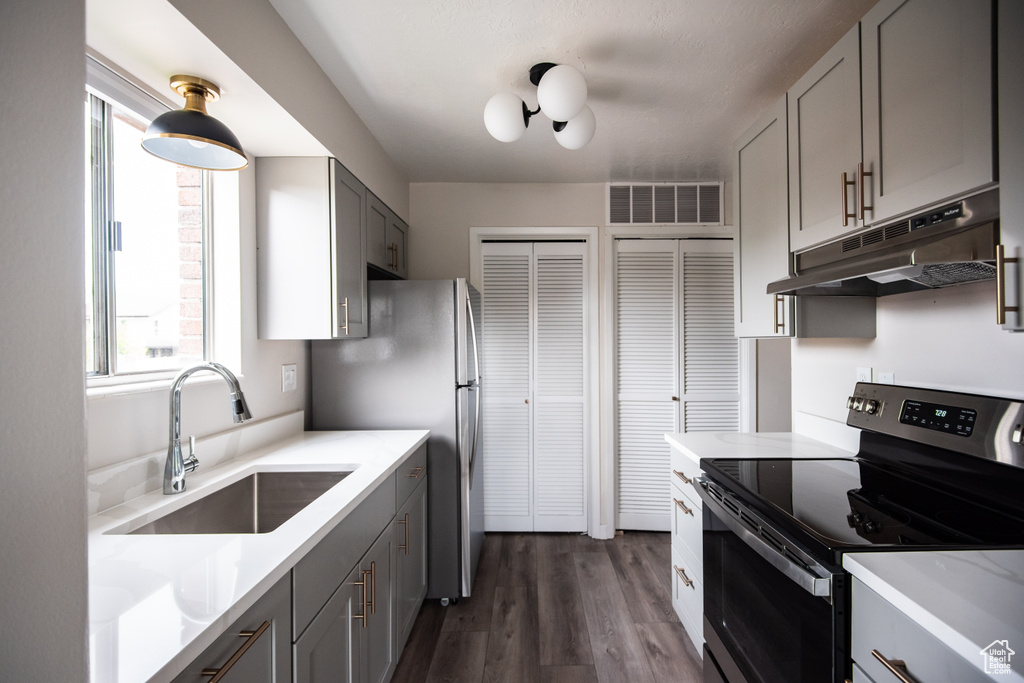 Kitchen featuring range with electric cooktop, under cabinet range hood, a sink, gray cabinets, and light countertops