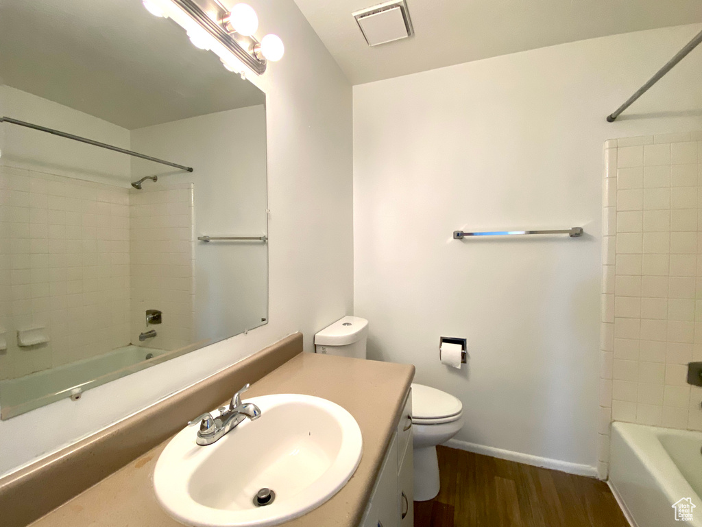Bathroom with vanity, shower / washtub combination, wood finished floors, toilet, and baseboards