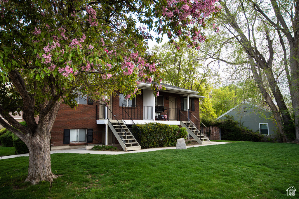View of front of property with stairway, brick siding, and a front lawn