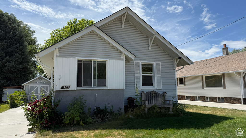 View of front of property featuring a front lawn and a storage shed