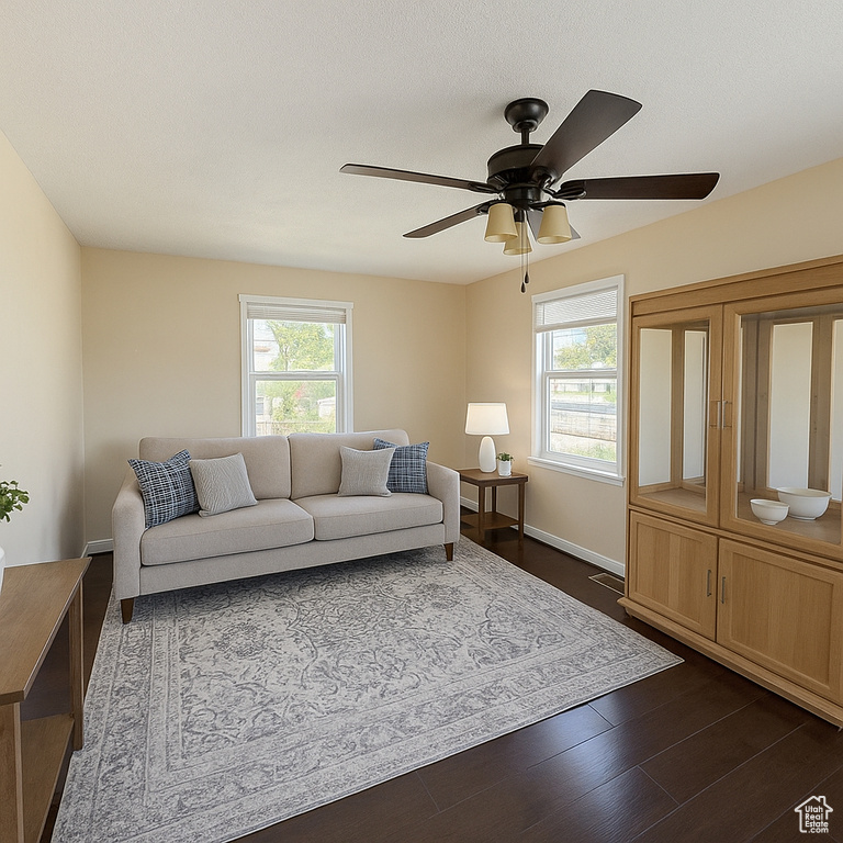 Living room with healthy amount of natural light, a ceiling fan, and dark wood finished floors