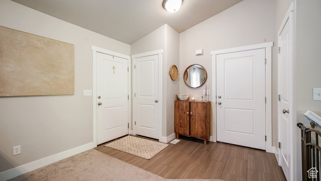 Entryway with baseboards, wood finished floors, and vaulted ceiling