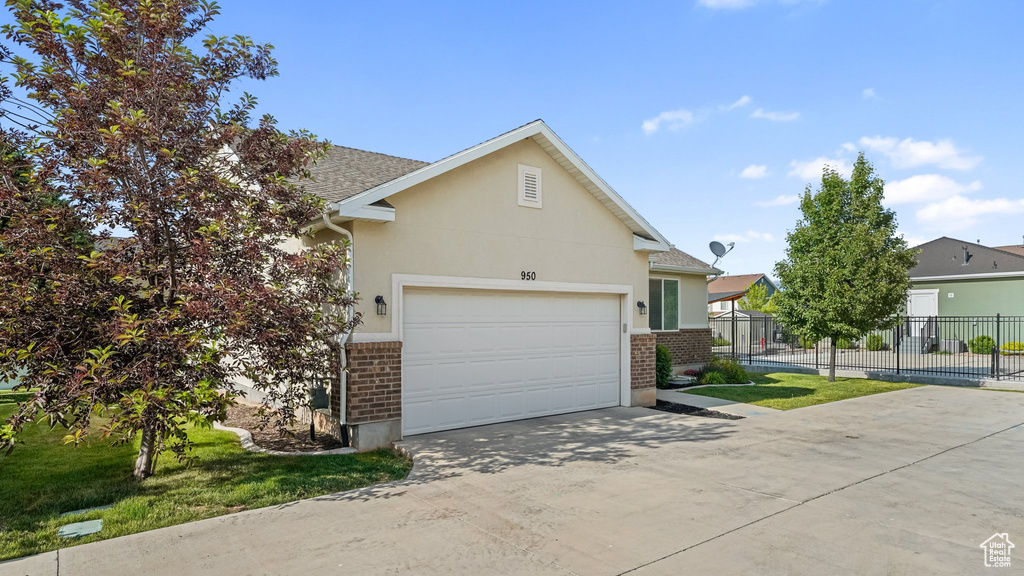 View of front of home with brick siding, driveway, an attached garage, and stucco siding