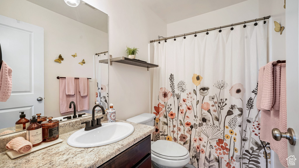 Bathroom with vanity, toilet, and a shower with shower curtain