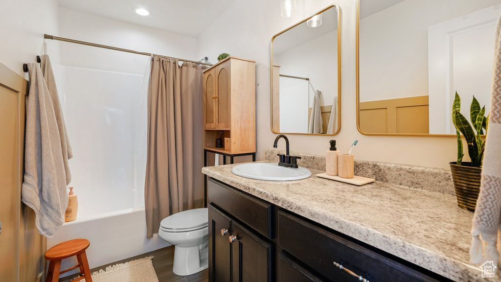 Bathroom with vanity, toilet, shower / bathtub combination with curtain, and wood finished floors