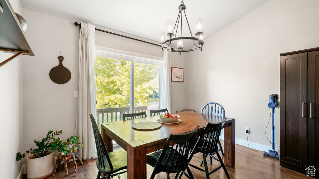 Dining area with a chandelier, wood finished floors, and baseboards