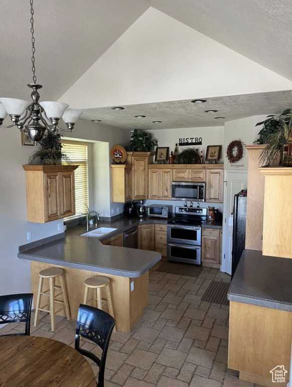 Kitchen featuring stainless steel appliances, a peninsula, high vaulted ceiling, a breakfast bar, and dark countertops
