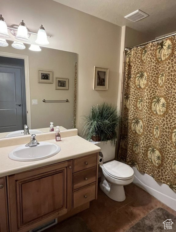 Full bathroom with vanity, tile patterned floors, shower / bath combo, and a textured ceiling