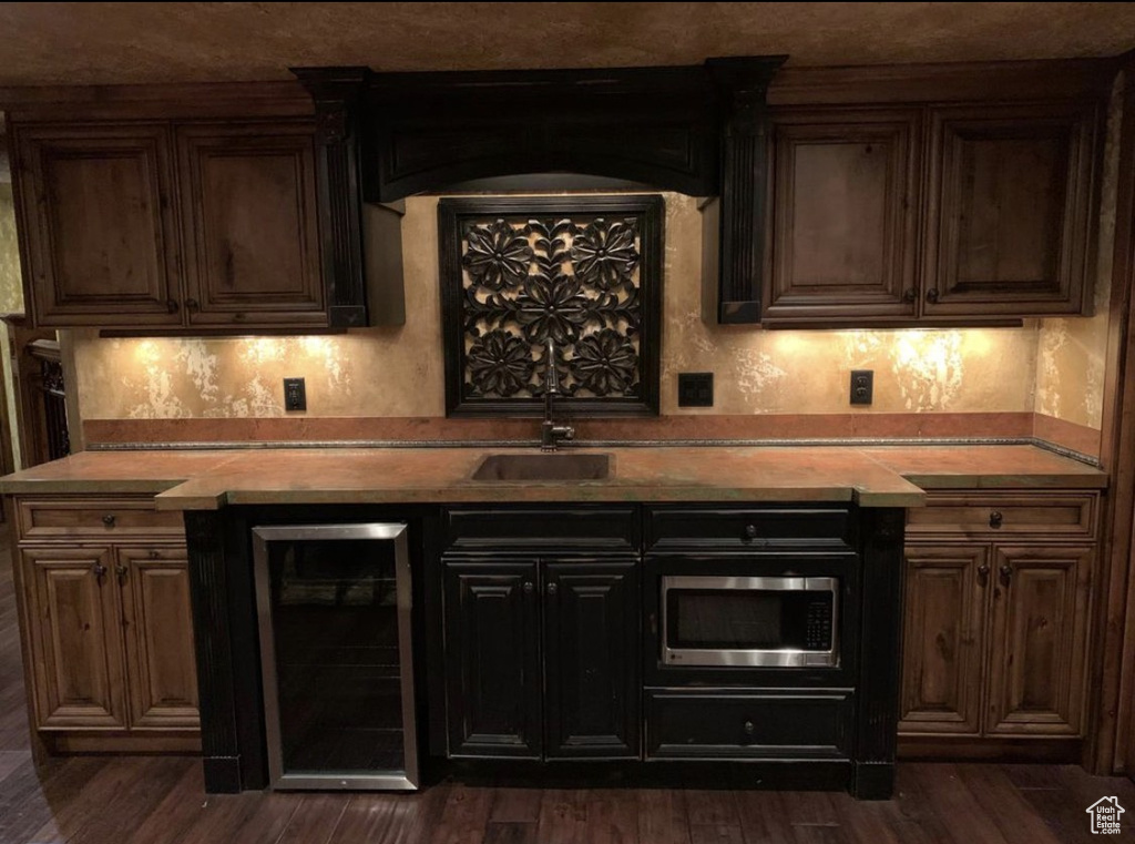 Indoor dry bar featuring wine cooler, stainless steel microwave, and dark wood-type flooring