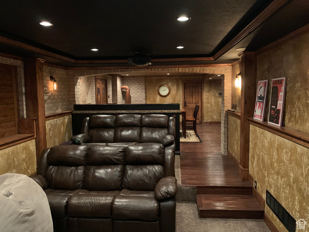 Cinema room with ornamental molding and wood-type flooring