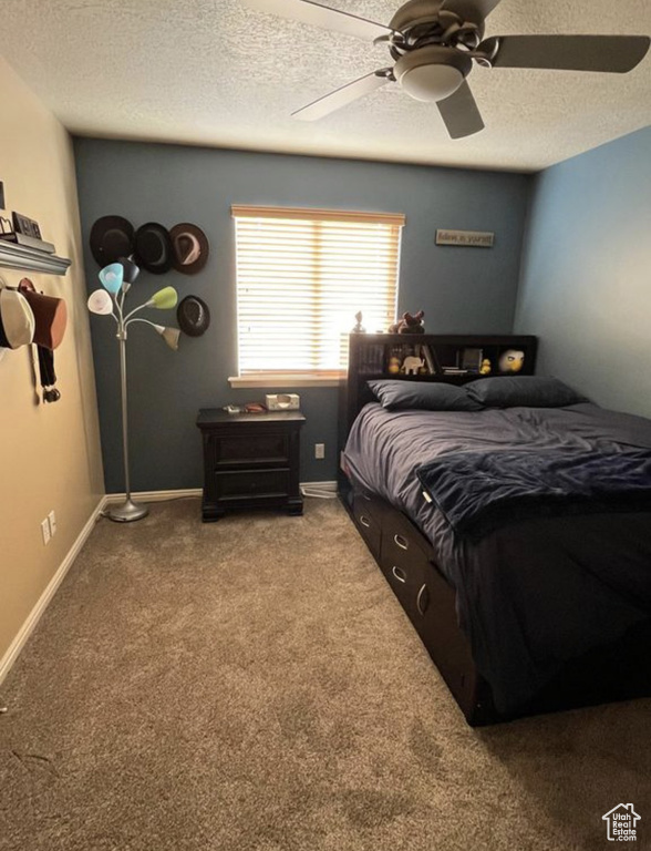 Carpeted bedroom with a textured ceiling and a ceiling fan
