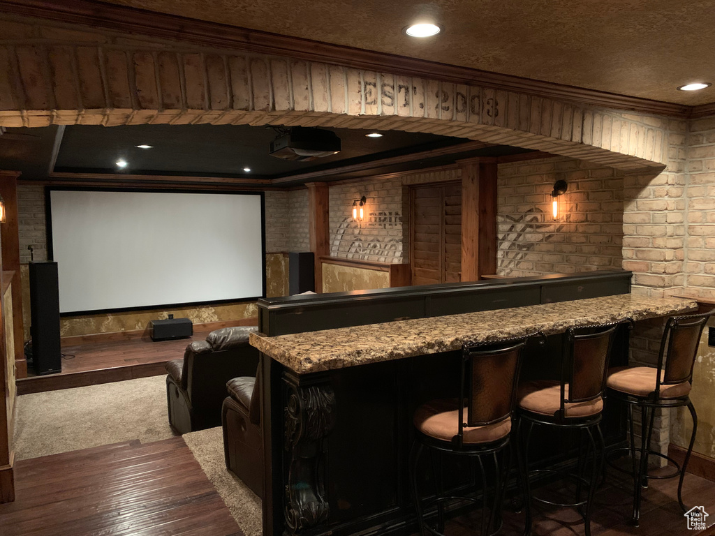 Home theater room with bar with sink, ornamental molding, wood-type flooring, recessed lighting, and a textured ceiling