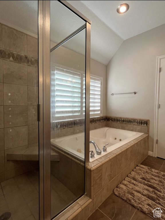 Full bath with a tub with jets, lofted ceiling, a stall shower, and tile patterned flooring