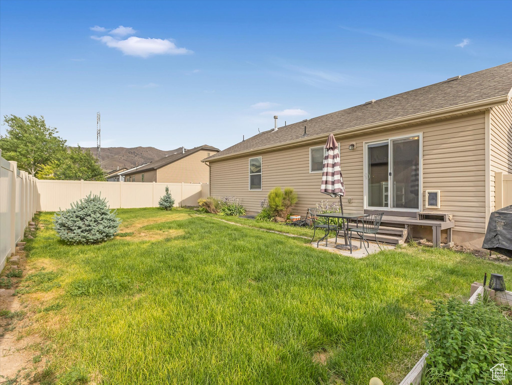 Rear view of house with a fenced backyard and a patio area
