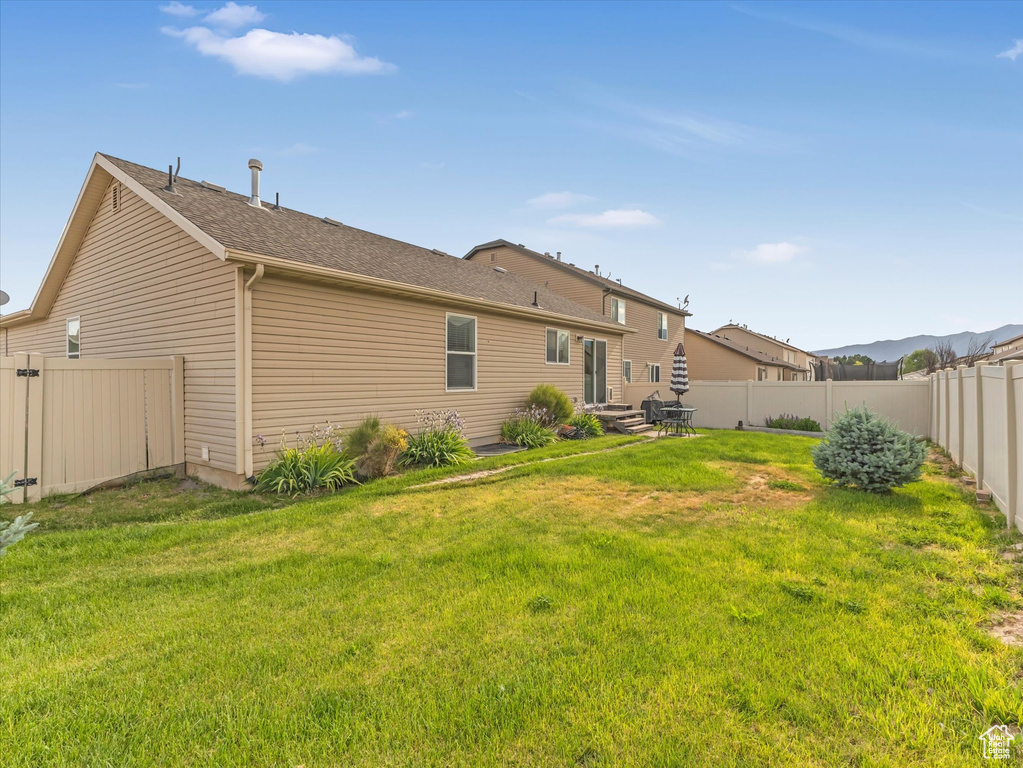Rear view of property featuring a fenced backyard and roof with shingles