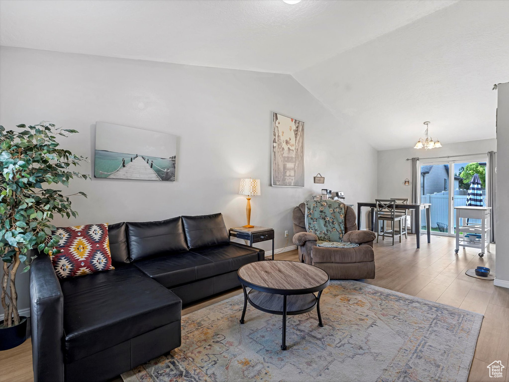 Living room featuring lofted ceiling, a chandelier, and wood finished floors