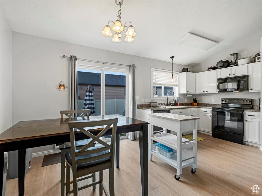 Kitchen featuring black appliances, white cabinetry, pendant lighting, and light wood-style flooring