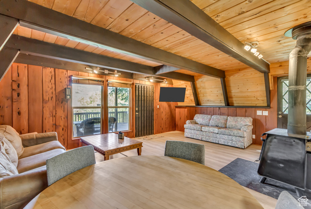 Living area featuring a wood stove, a wooden ceiling with exposed beams, wood walls, and wood finished floors