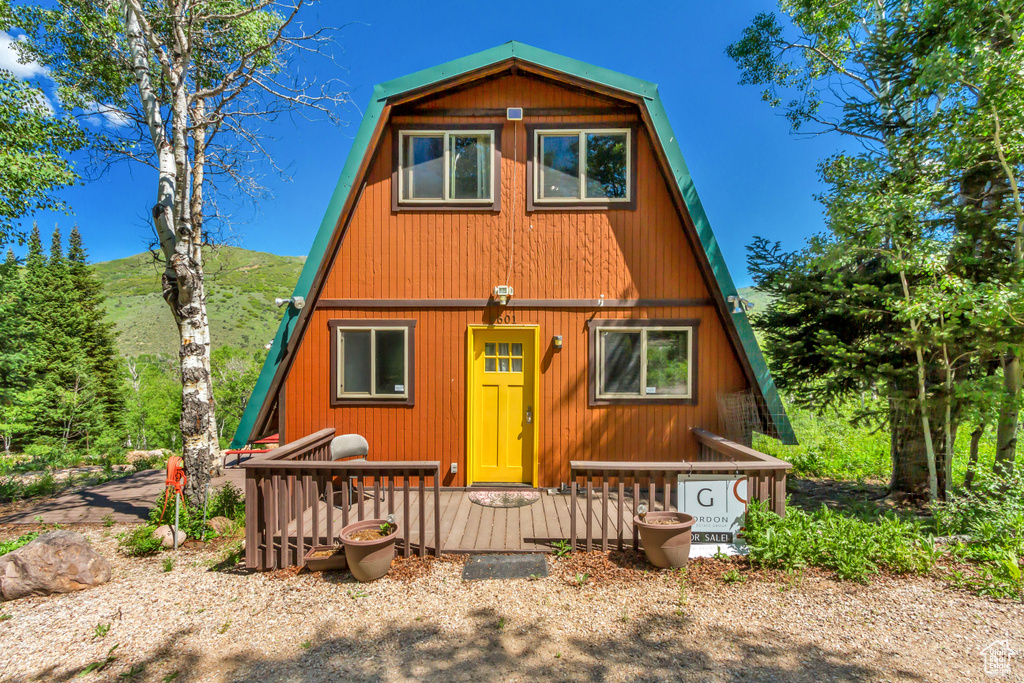 A-frame style home with a gambrel roof and a wooden deck