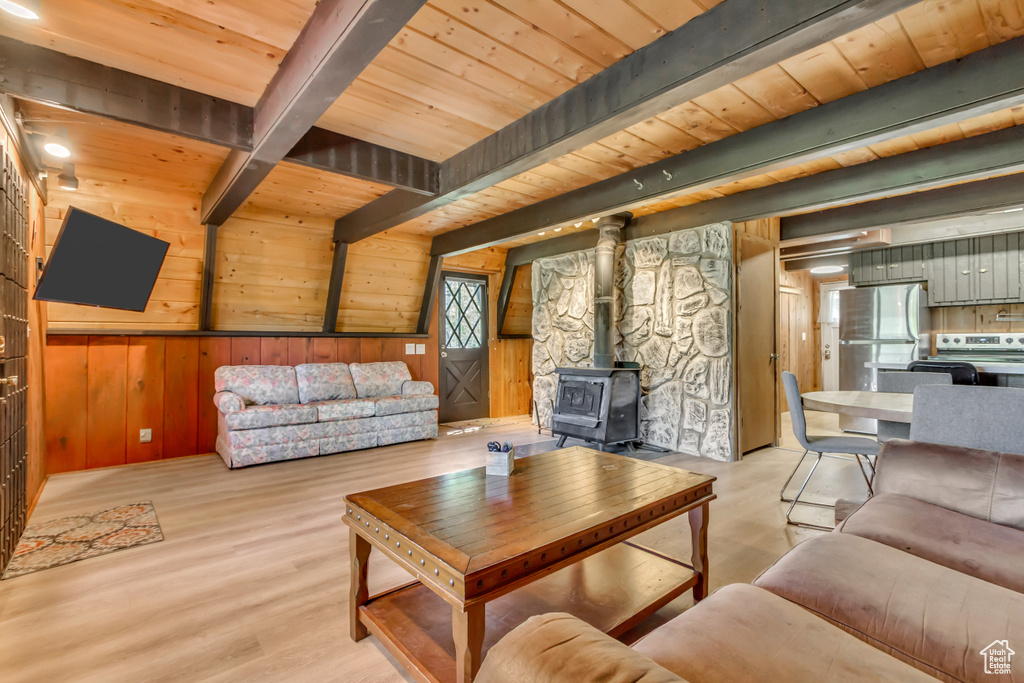 Living area featuring a wood ceiling with exposed beams, a wood stove, wood walls, and wood finished floors