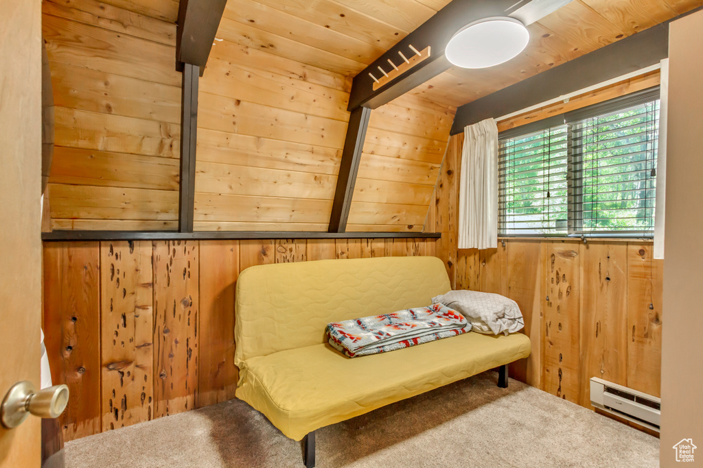 Sitting room featuring baseboard heating, wood walls, and carpet floors