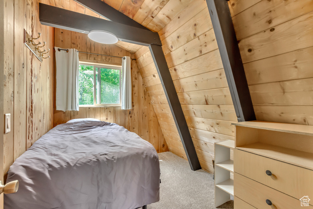 Bedroom featuring vaulted ceiling, wooden walls, and carpet