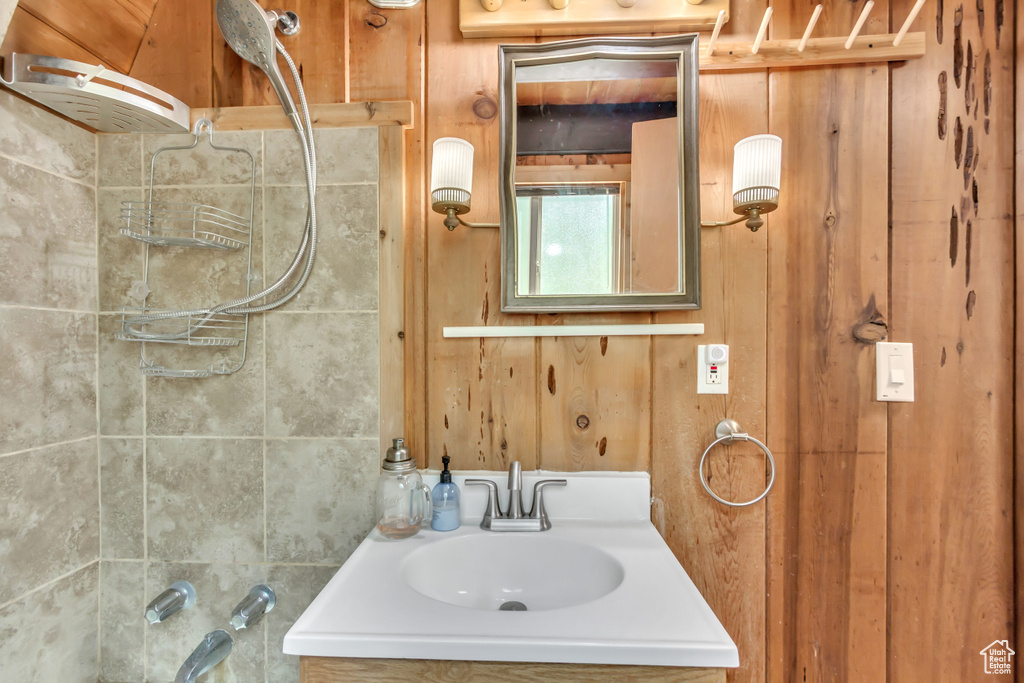 Bathroom featuring vanity, wood walls, and bathtub / shower combination