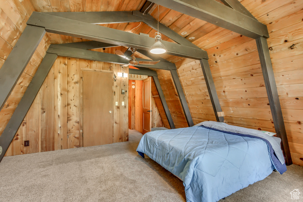 Carpeted bedroom with vaulted ceiling, wooden walls, and wood ceiling