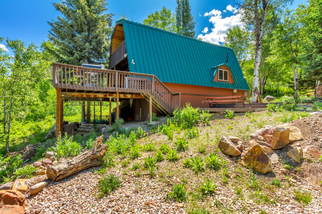 Back of property featuring a metal roof, a wooden deck, stairs, and a gambrel roof