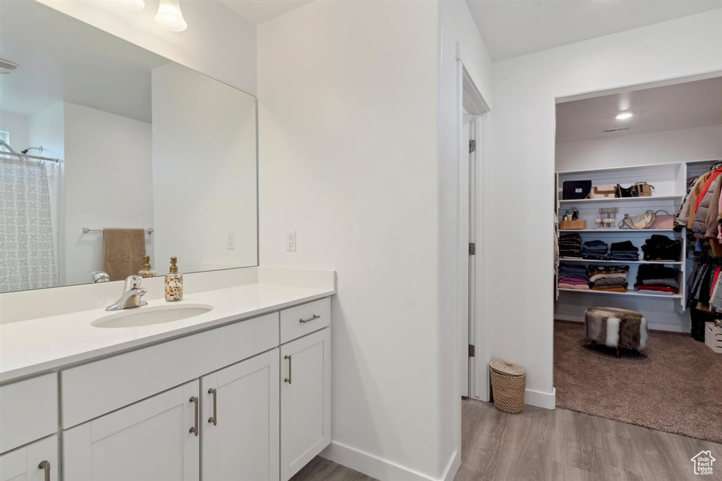 Full bath featuring vanity, wood finished floors, and a walk in closet