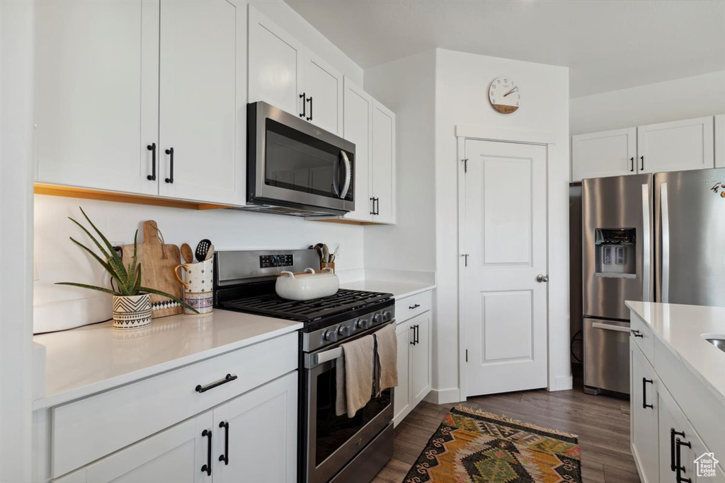 Kitchen featuring appliances with stainless steel finishes, dark wood finished floors, and light countertops