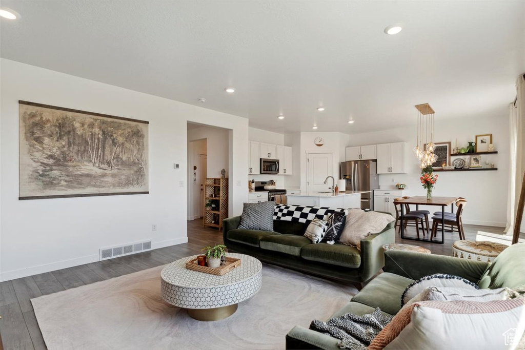 Living area featuring dark wood-style flooring, recessed lighting, and a chandelier