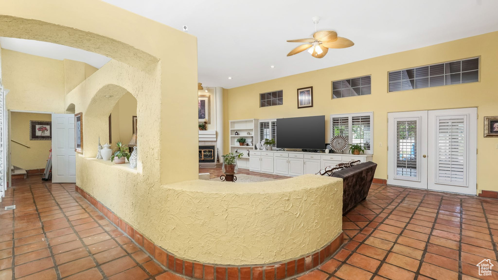 Living area with a towering ceiling, ceiling fan, arched walkways, tile patterned floors, and recessed lighting