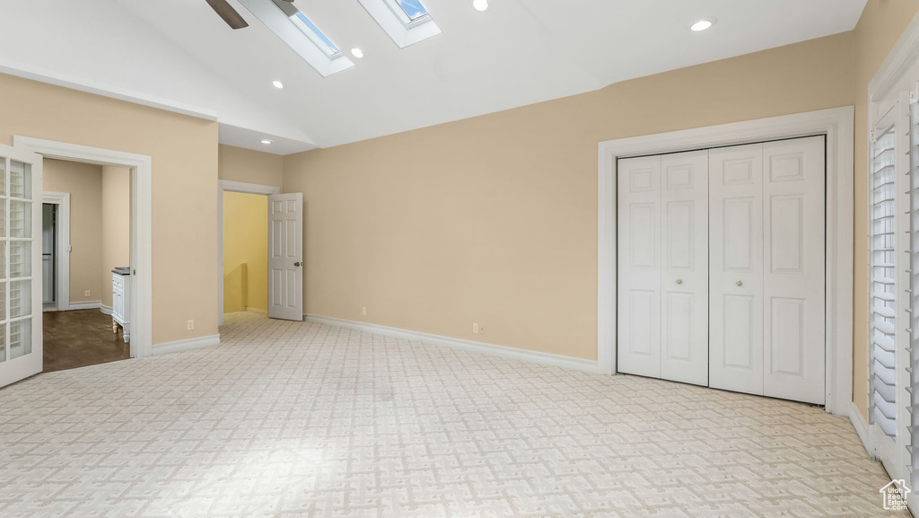 Unfurnished bedroom featuring a skylight, carpet flooring, lofted ceiling, recessed lighting, and a closet