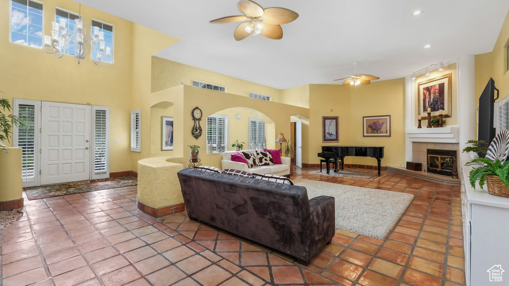 Living area with a ceiling fan, a tile fireplace, arched walkways, tile patterned floors, and recessed lighting