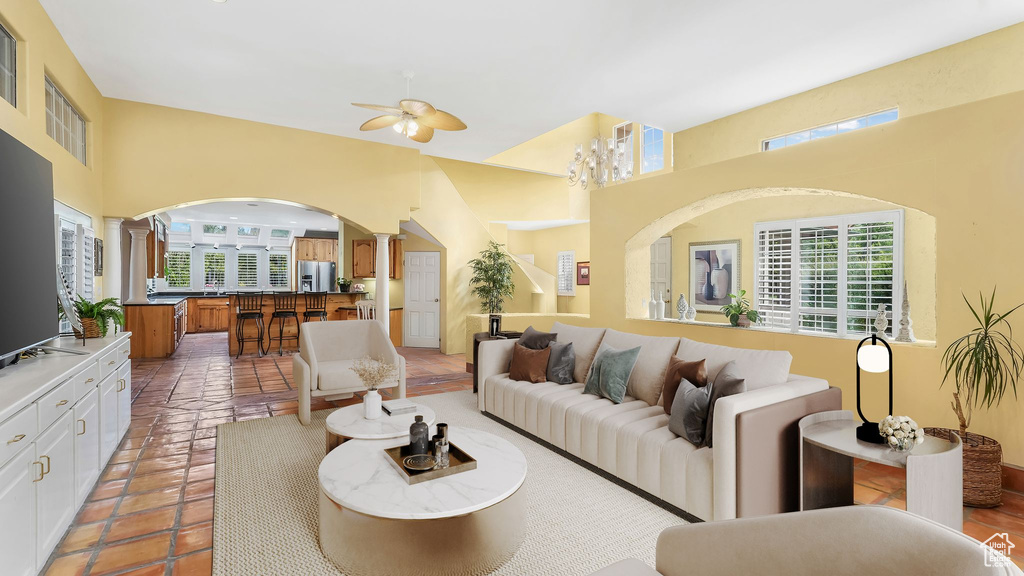 Living area with decorative columns, arched walkways, a towering ceiling, and ceiling fan