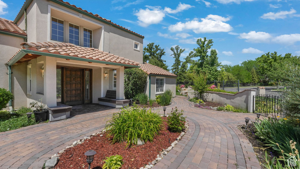 Mediterranean / spanish-style house featuring a tile roof, stucco siding, a gate, and a porch