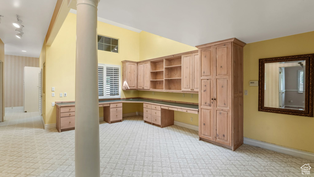 Unfurnished office with built in desk, light colored carpet, and rail lighting