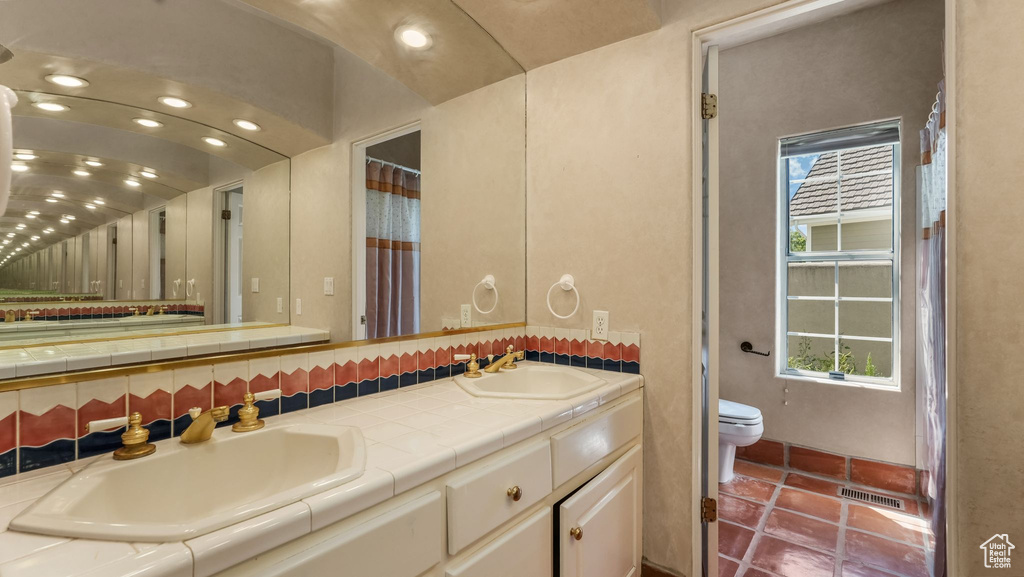 Full bathroom with double vanity, plenty of natural light, tile patterned floors, and recessed lighting