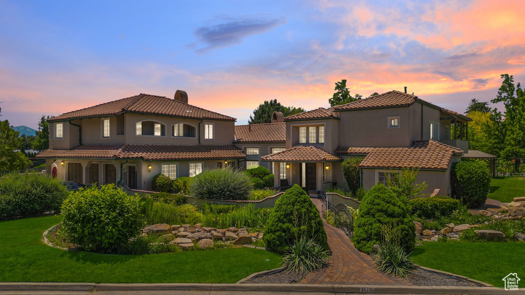 Mediterranean / spanish-style house featuring stucco siding, a tile roof, and a front yard